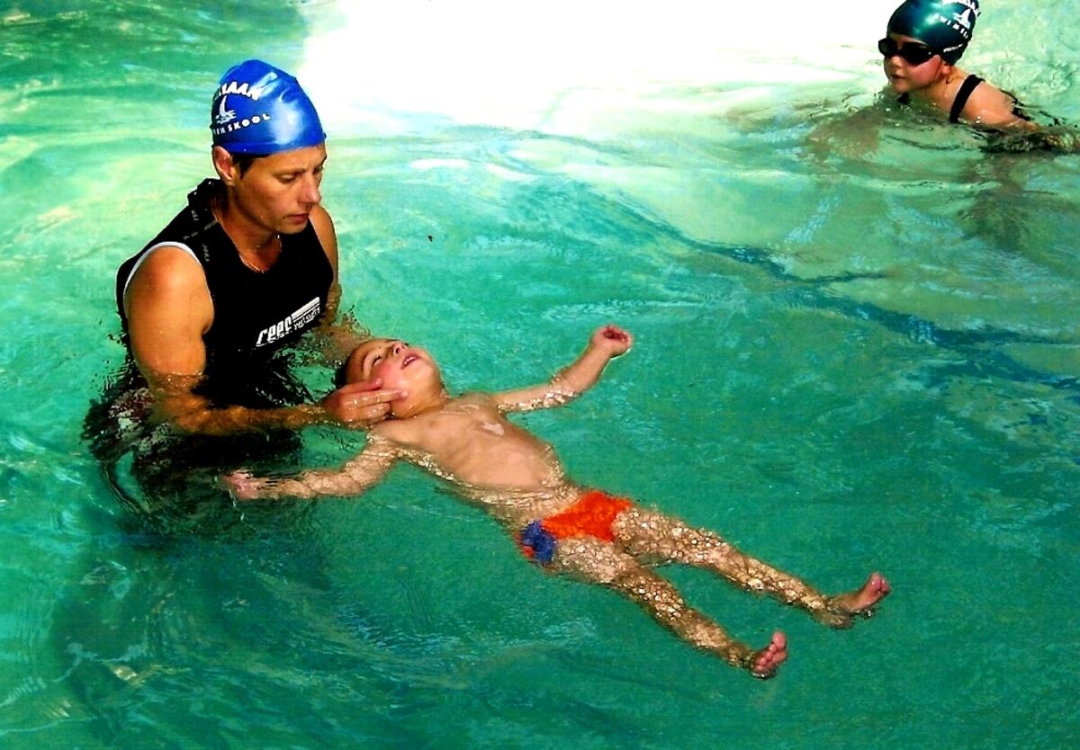 Instructor teaching a child to float on his back