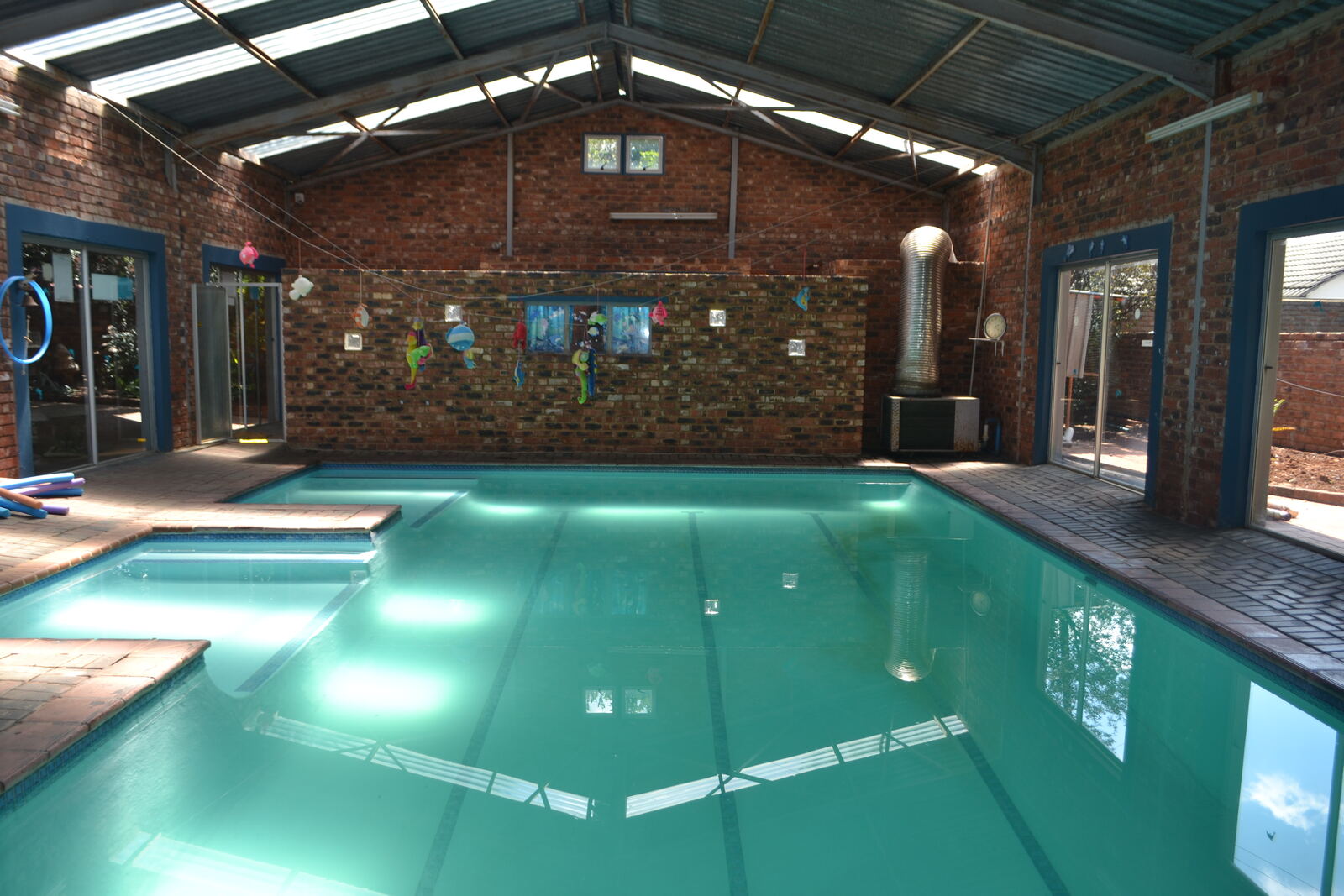 Indoor heated swimming pool with brick walls and colourful decorations