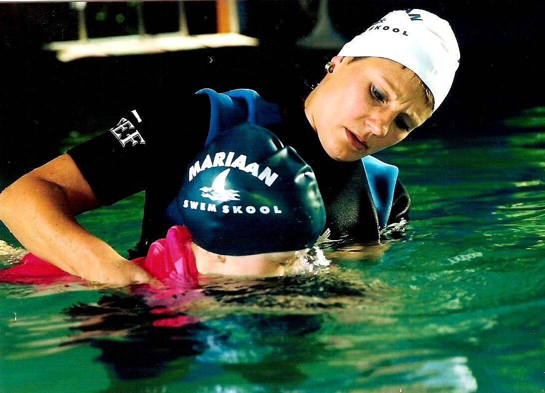 Instructor in a Mariaan swim cap helping a learner