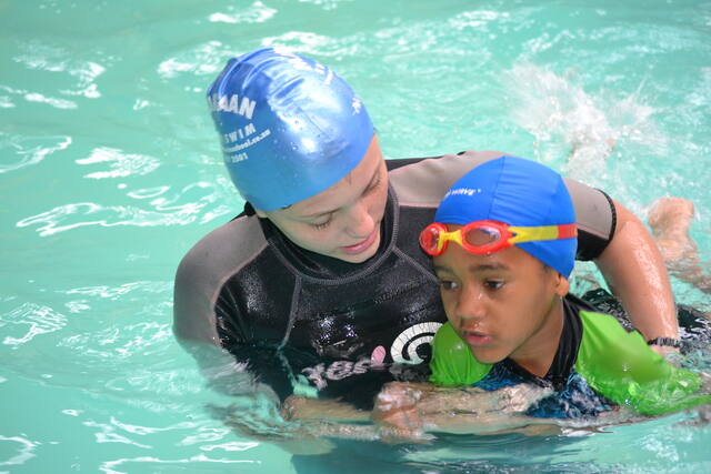 Instructor guiding a young learner in goggles