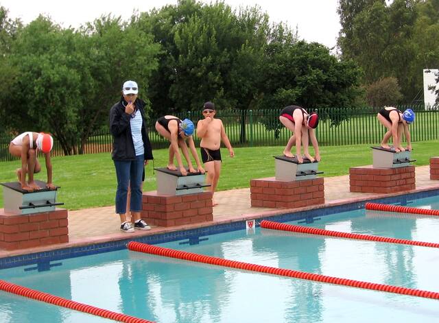 Swimmers ready on the starting blocks at a gala
