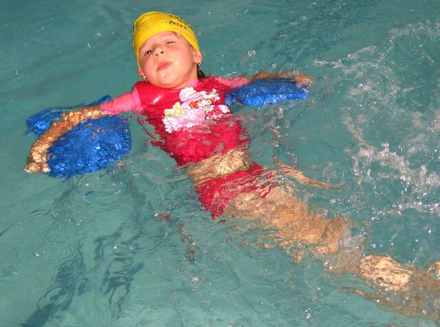 Young girl floating with arm floats