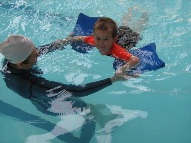 Instructor and boy practising with kickboards