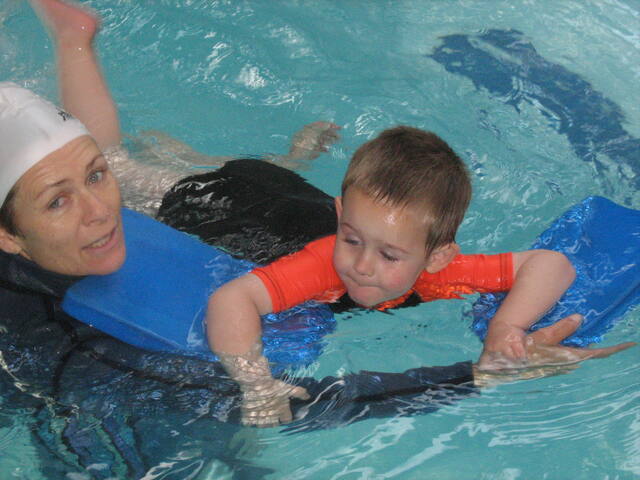 Smiling boy with kickboards and his instructor