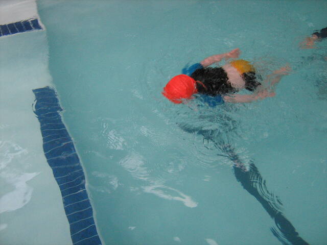 Child in an orange cap swimming