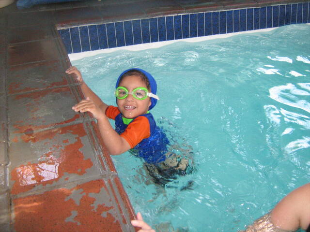 Smiling child with goggles at the pool wall